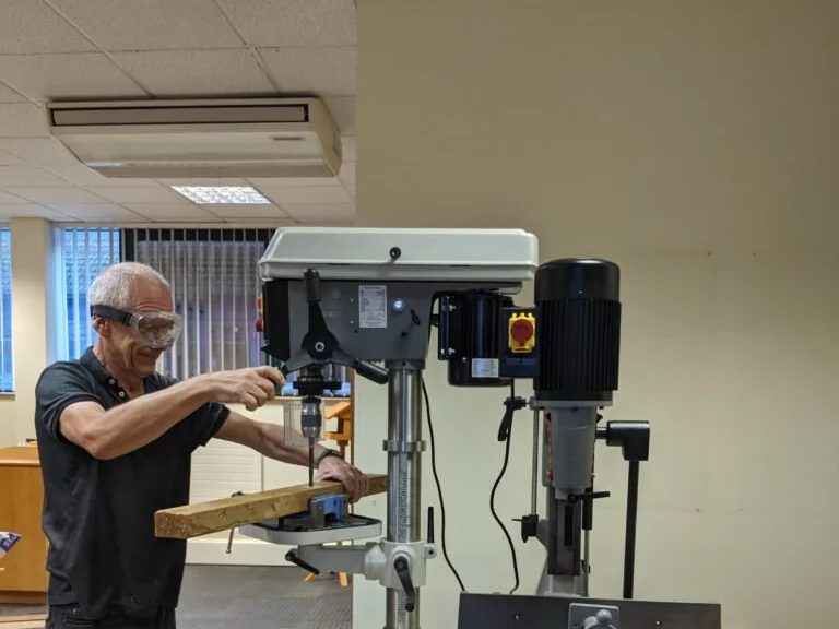 A volunteer working at the pillar drill in the Useful Wood Company workshop